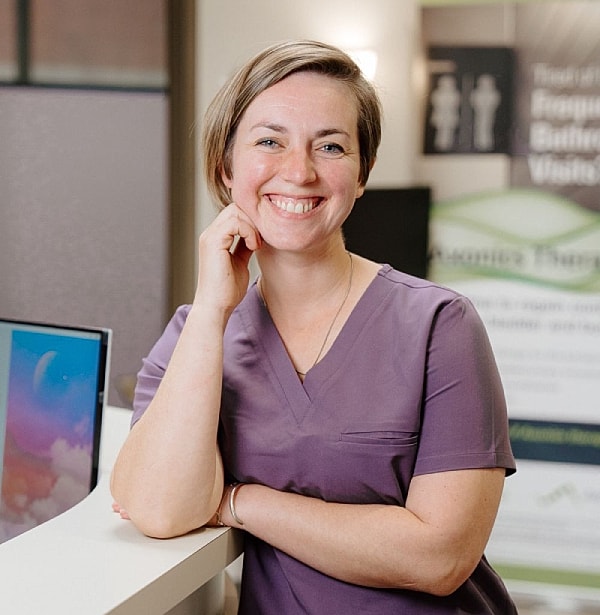 Smiling woman in purple scrubs at reception.