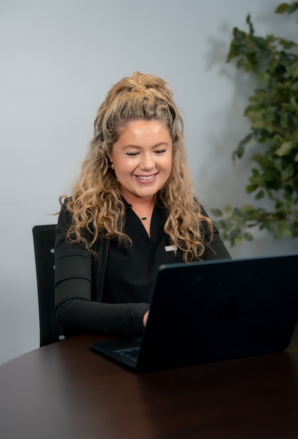 Smiling woman working on a laptop.