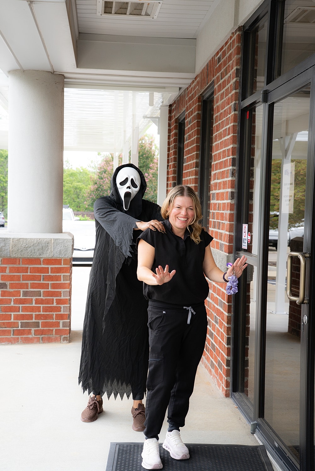 Woman with ghostface costume in playful pose.