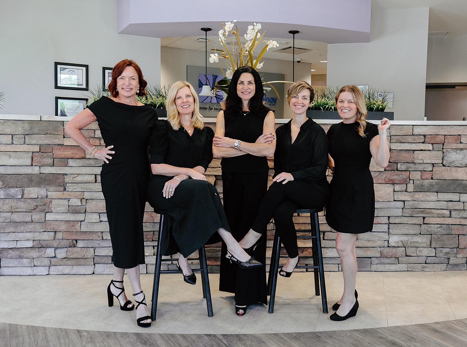 Group of women posing together in black outfits.